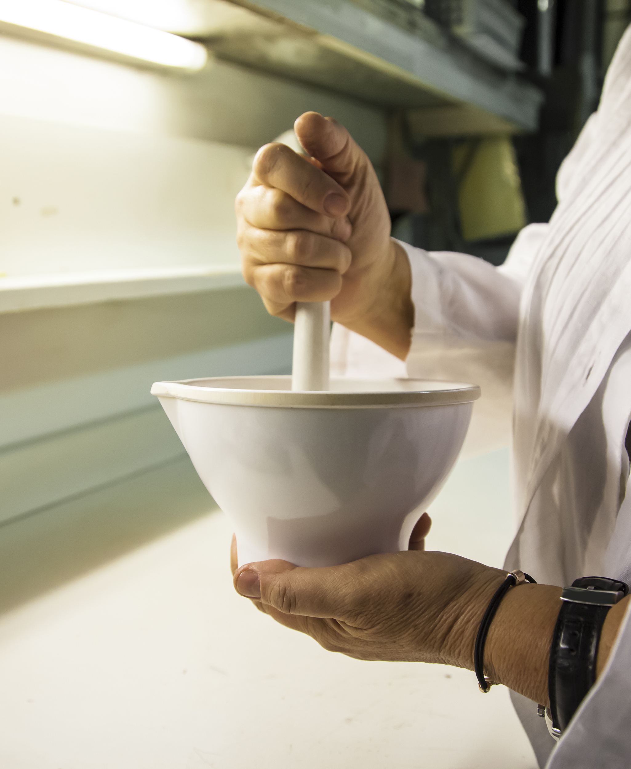 Scientist grinds up compound in porcelain mortar using a pestle